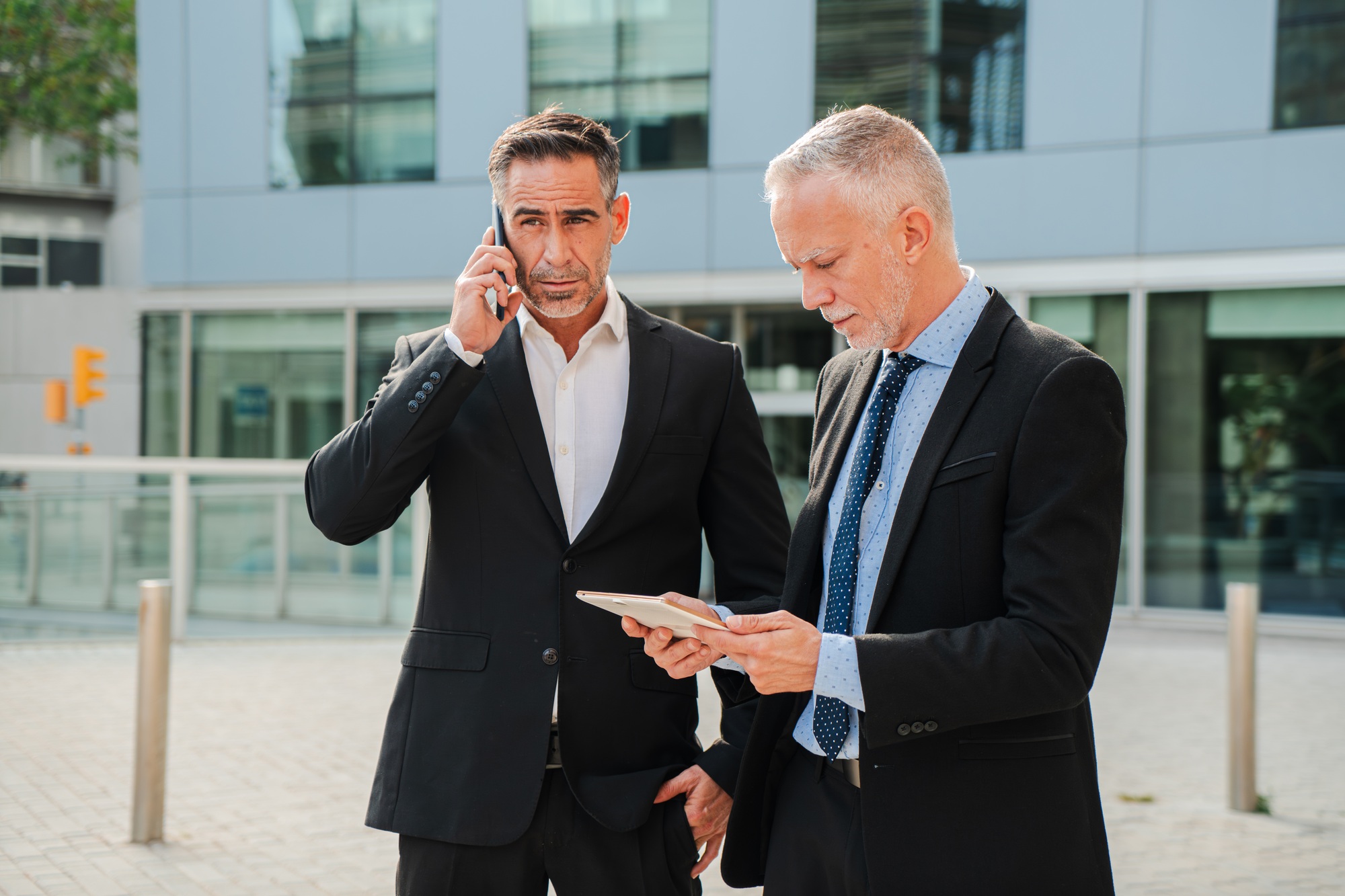 Two Businessmen are Actively Engaged in Important Conversations. One is Talking on the Phone While