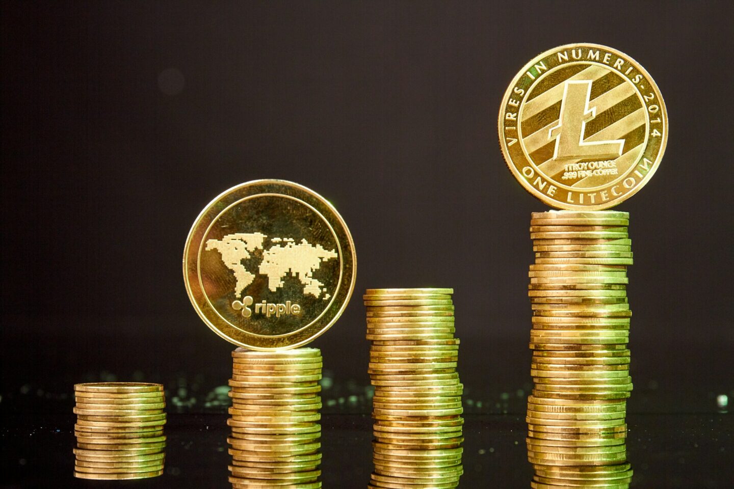Stacks of litecoins and ripple coins on dark background