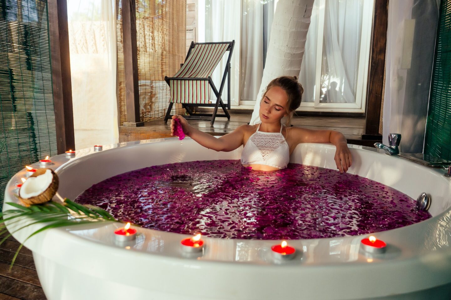 Woman relaxing in bath with tropical flowers outdoor at luxury hotel